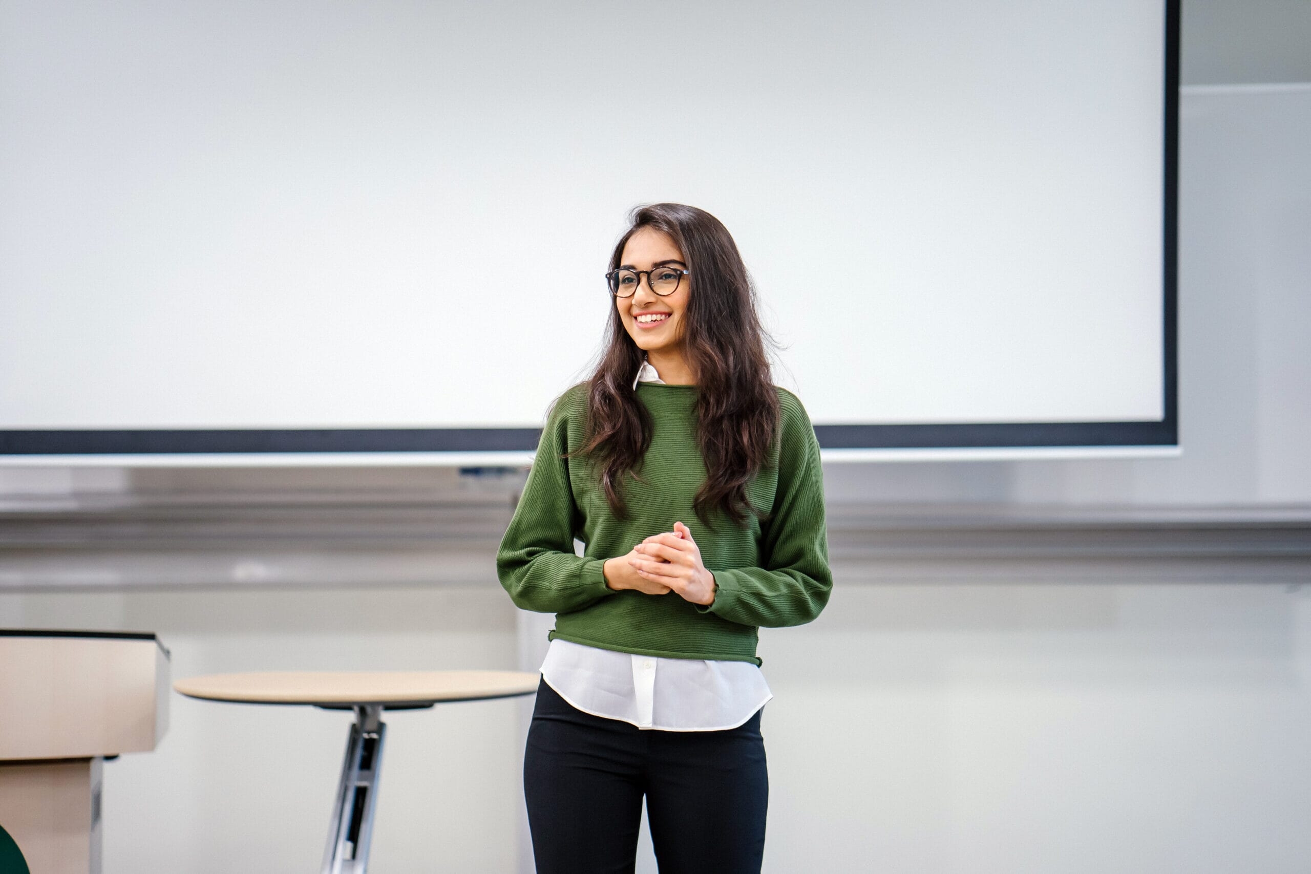 A young and intelligent-looking woman giving a business presentation to an audience.