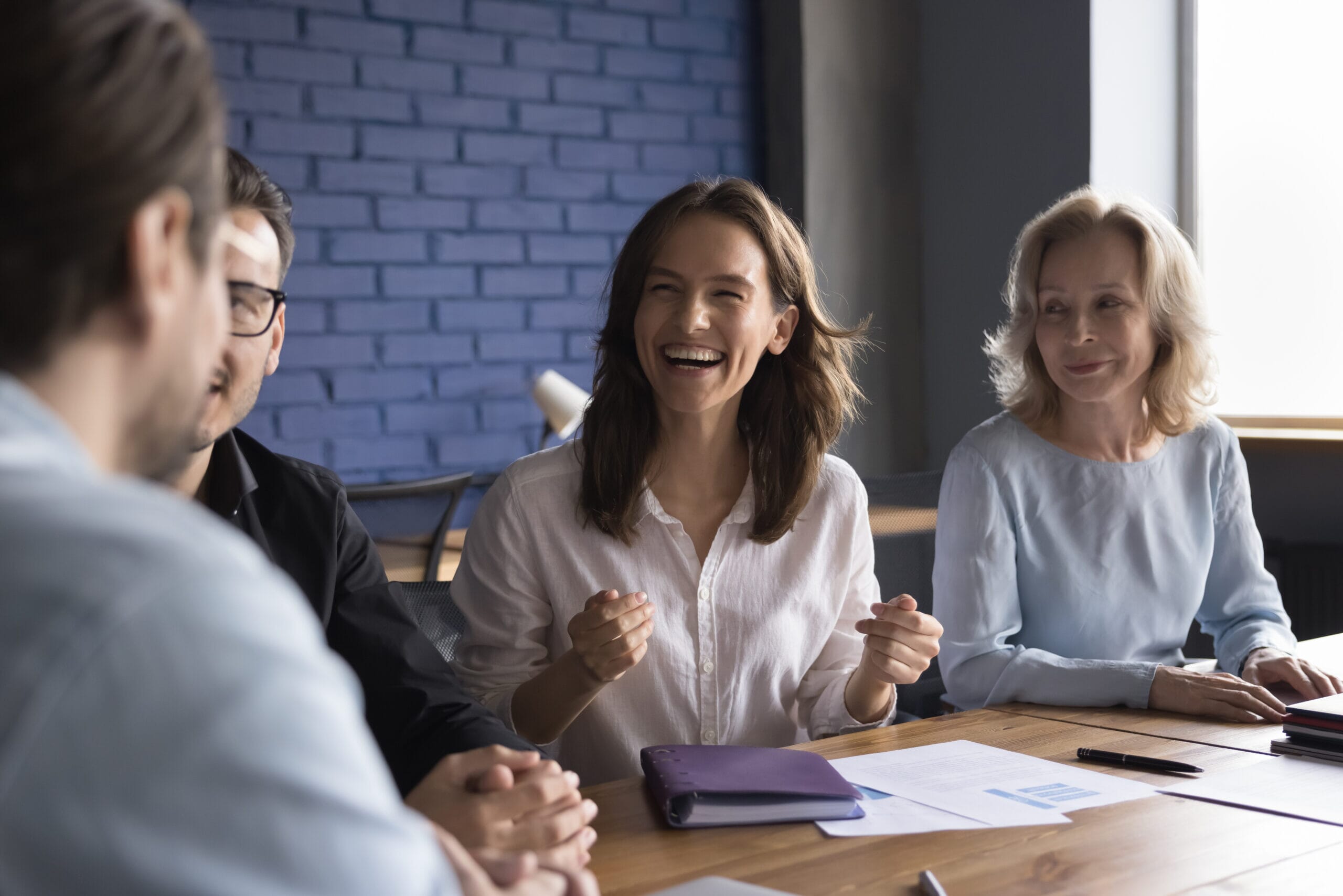 Cheerful woman meeting with colleagues at table